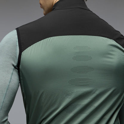 Person wearing a green and black jacket with perforated design on the back against a gray background