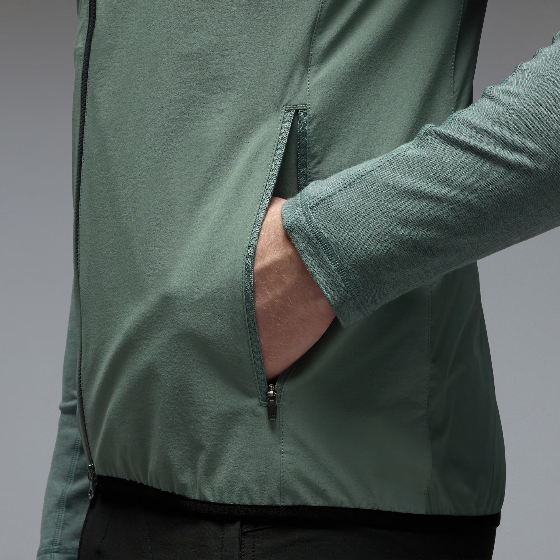 Person wearing a green jacket with a gray background