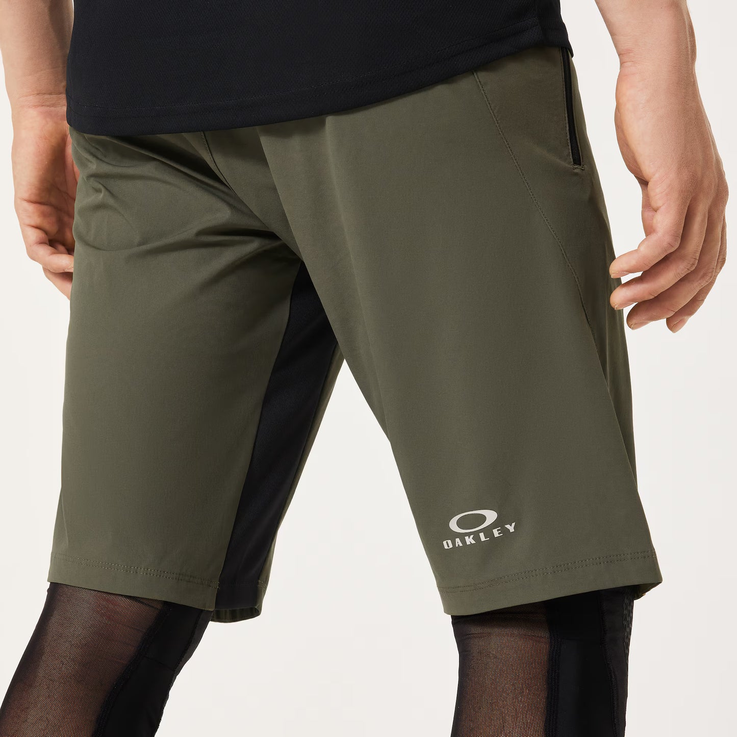 Green shorts with Oakley logo worn by a person on a light gray background