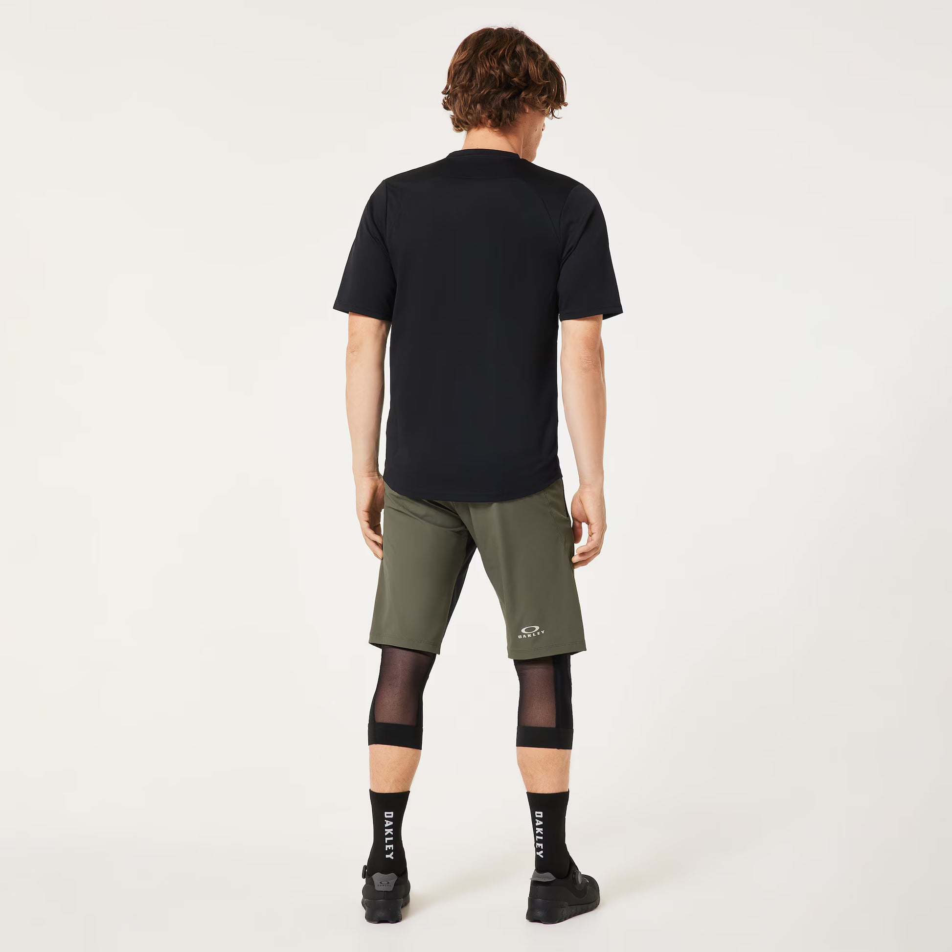 Person wearing a black t-shirt and green shorts on a white background