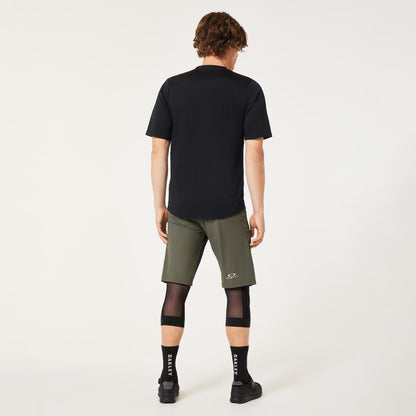 Person wearing a black t-shirt and green shorts on a white background