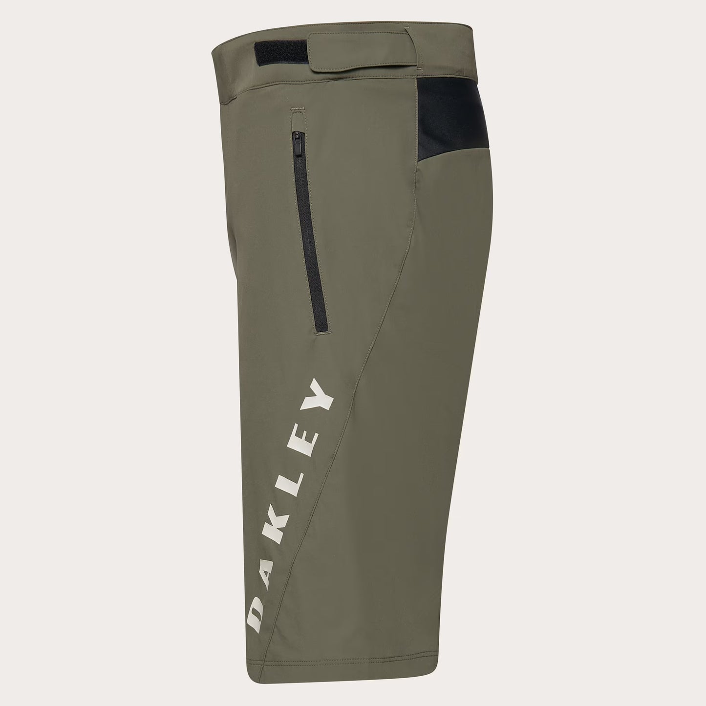 Olive green Oakley cycling shorts with a vertical white 'OAKLEY' logo on the left leg, a black zippered pocket, and a black side panel near the hip, shown against a light gray background.