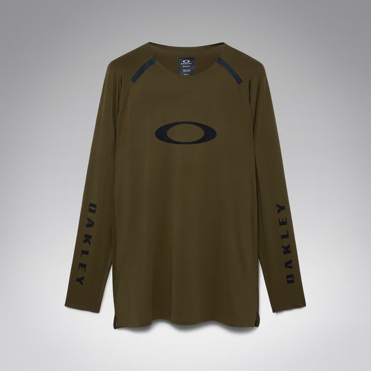 An olive brown long-sleeve athletic shirt by Oakley, featuring a large black Oakley logo on the chest, black vertical branding on both sleeves, and black shoulder detailing, shown against a neutral gray background.