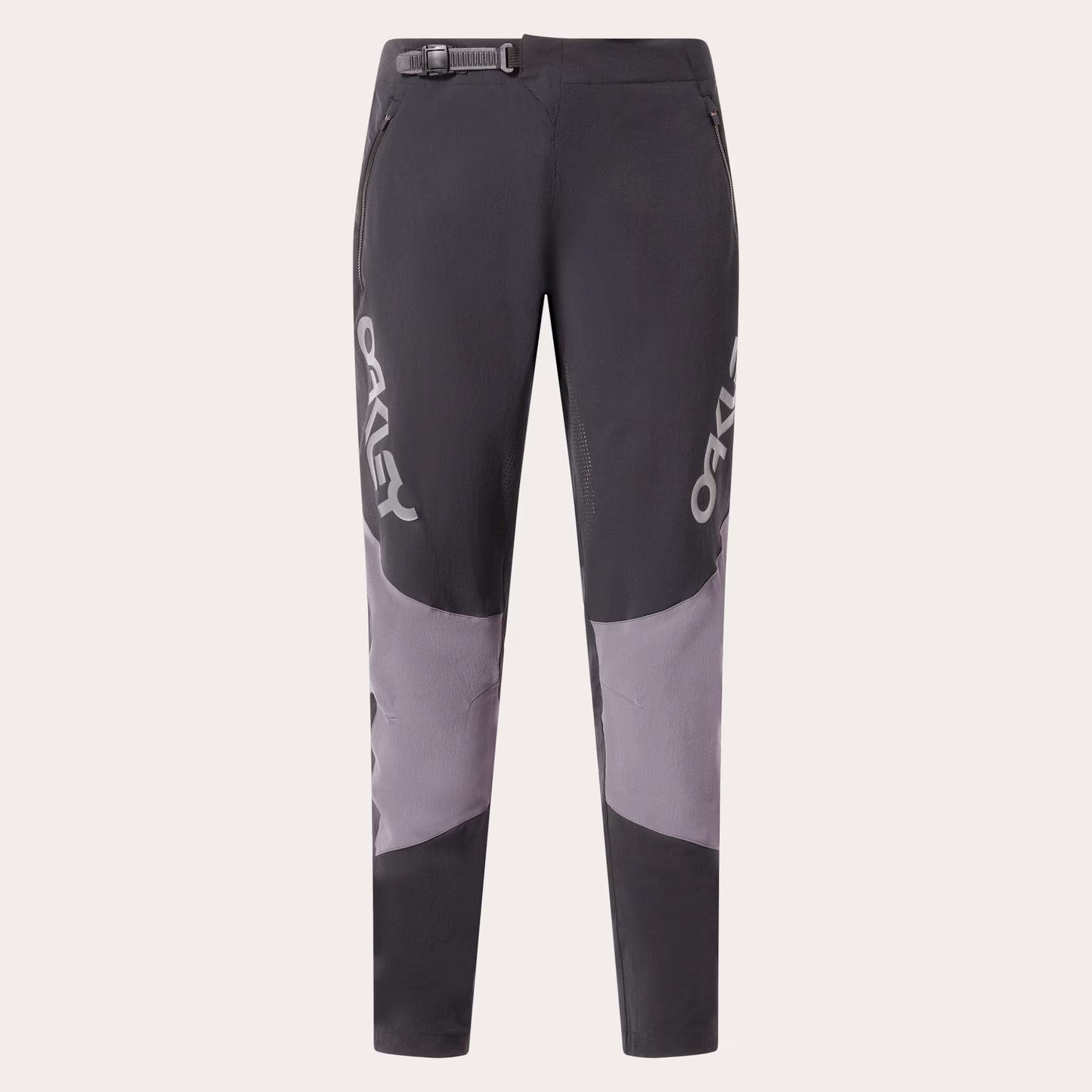 A pair of dark gray and light gray colorblock mountain biking pants with white OAKLEY branding printed vertically on the sides, shown against a light gray background.