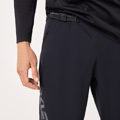 Close-up of a person wearing dark athletic pants and a black long-sleeve top, showing the side pocket and zipper detail against a clean white background.