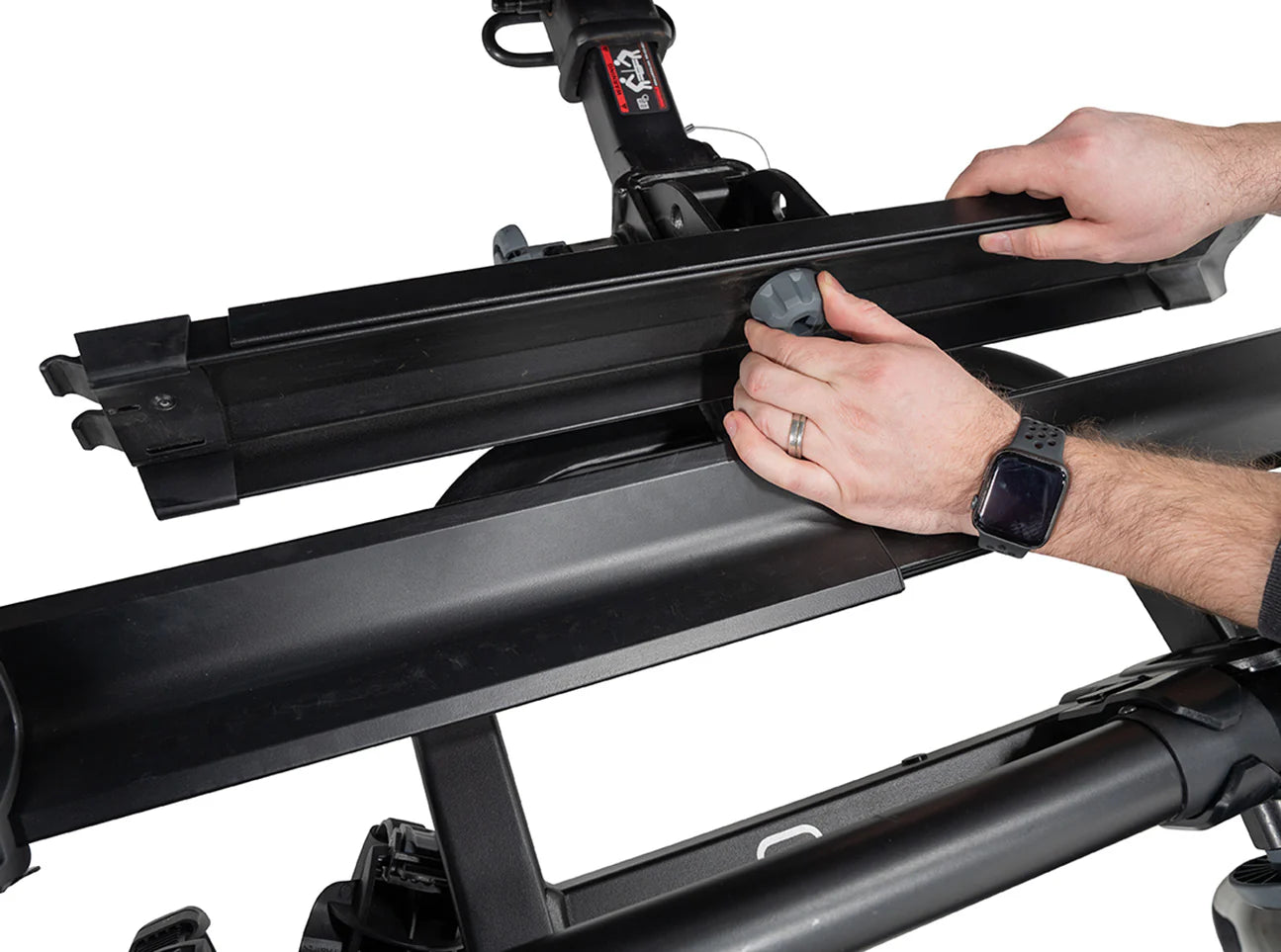 Person adjusting a black roof rack system on a vehicle