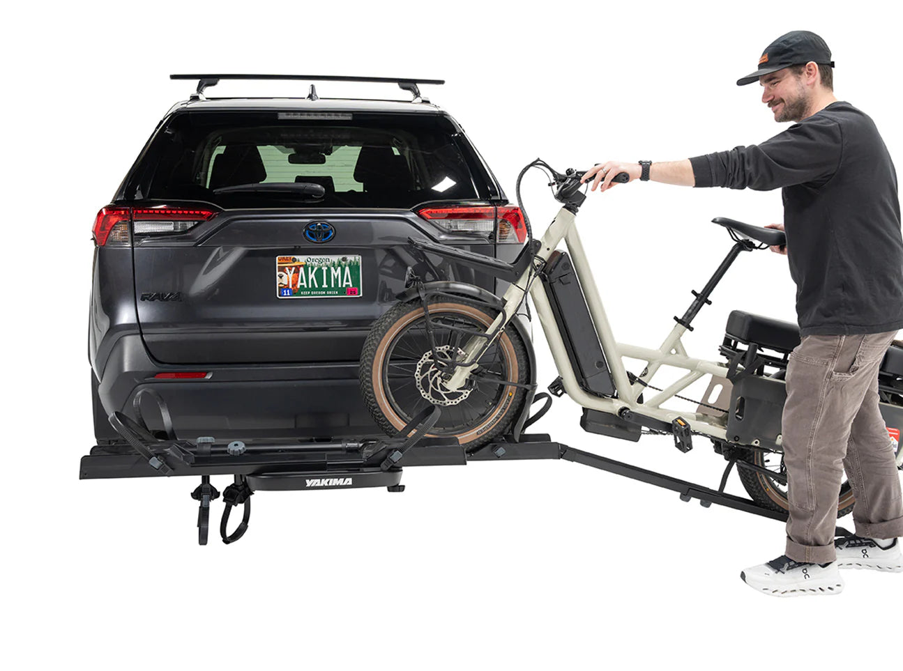 Man attaching a bicycle to a car with a bike rack on a white background