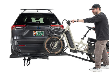 Man attaching a bicycle to a car with a bike rack on a white background