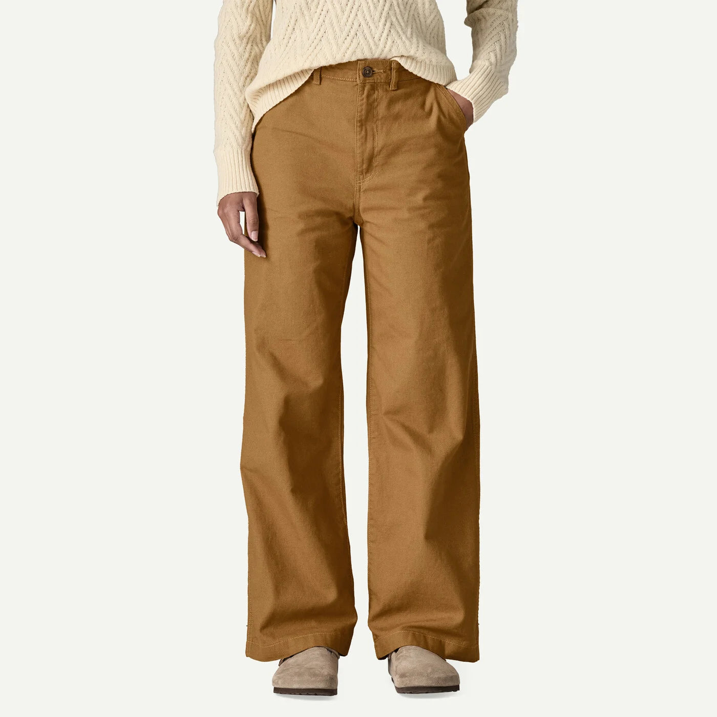 Person wearing brown pants and a cream sweater on a white background
