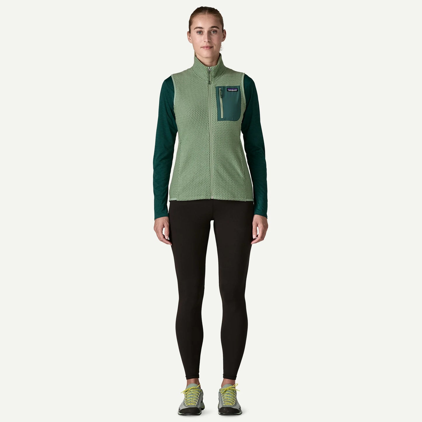 Person wearing a green and black jacket with a pocket on a white background