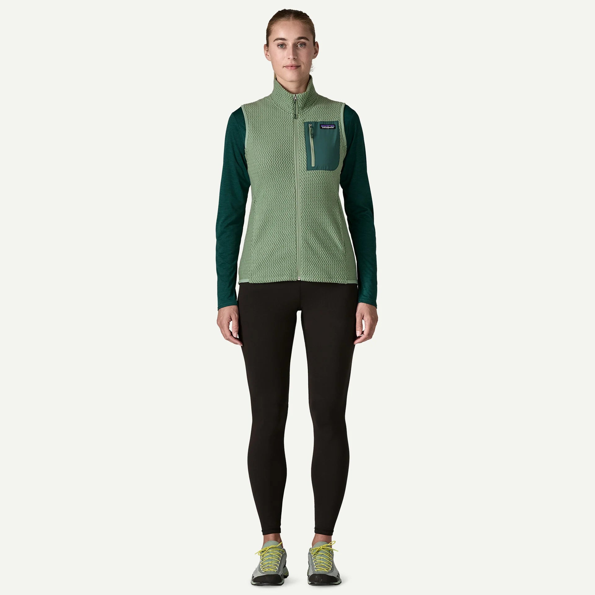 Person wearing a green and black jacket with a pocket on a white background