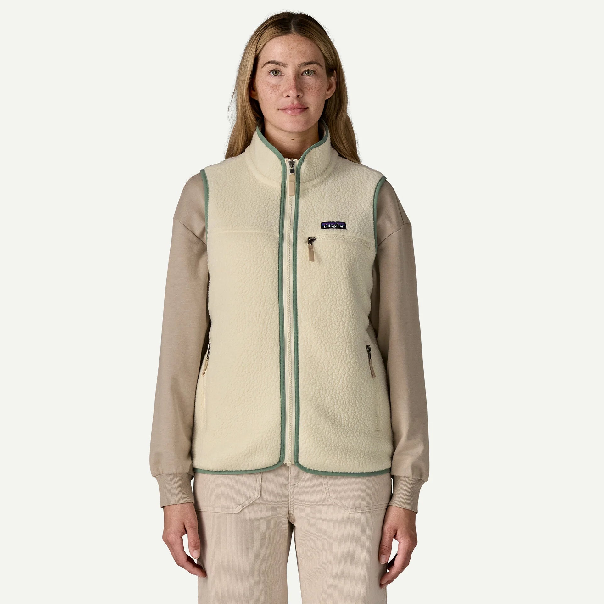 Woman wearing a beige fleece vest with a visible brand logo on a white background