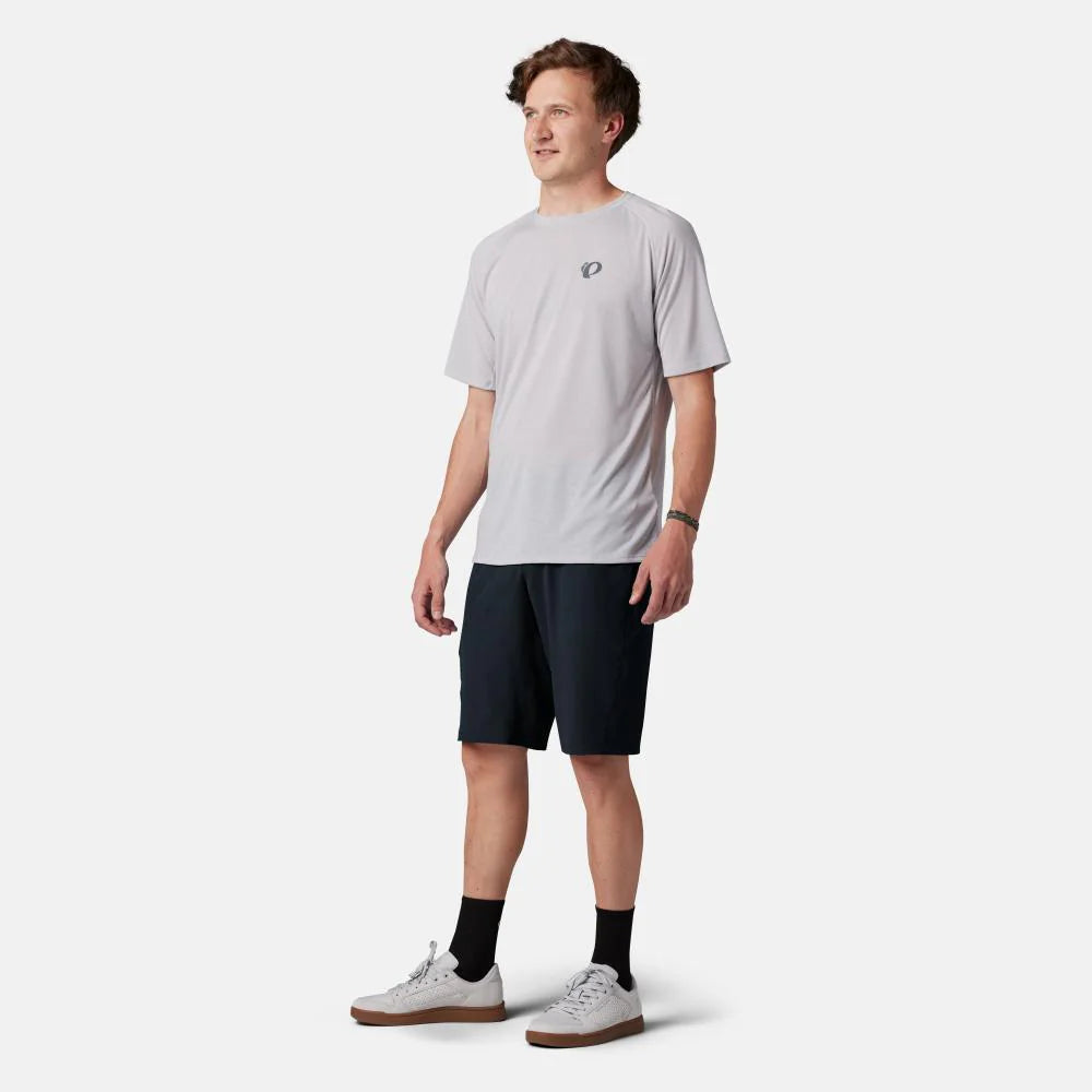 Man wearing a light gray t-shirt and dark shorts on a white background