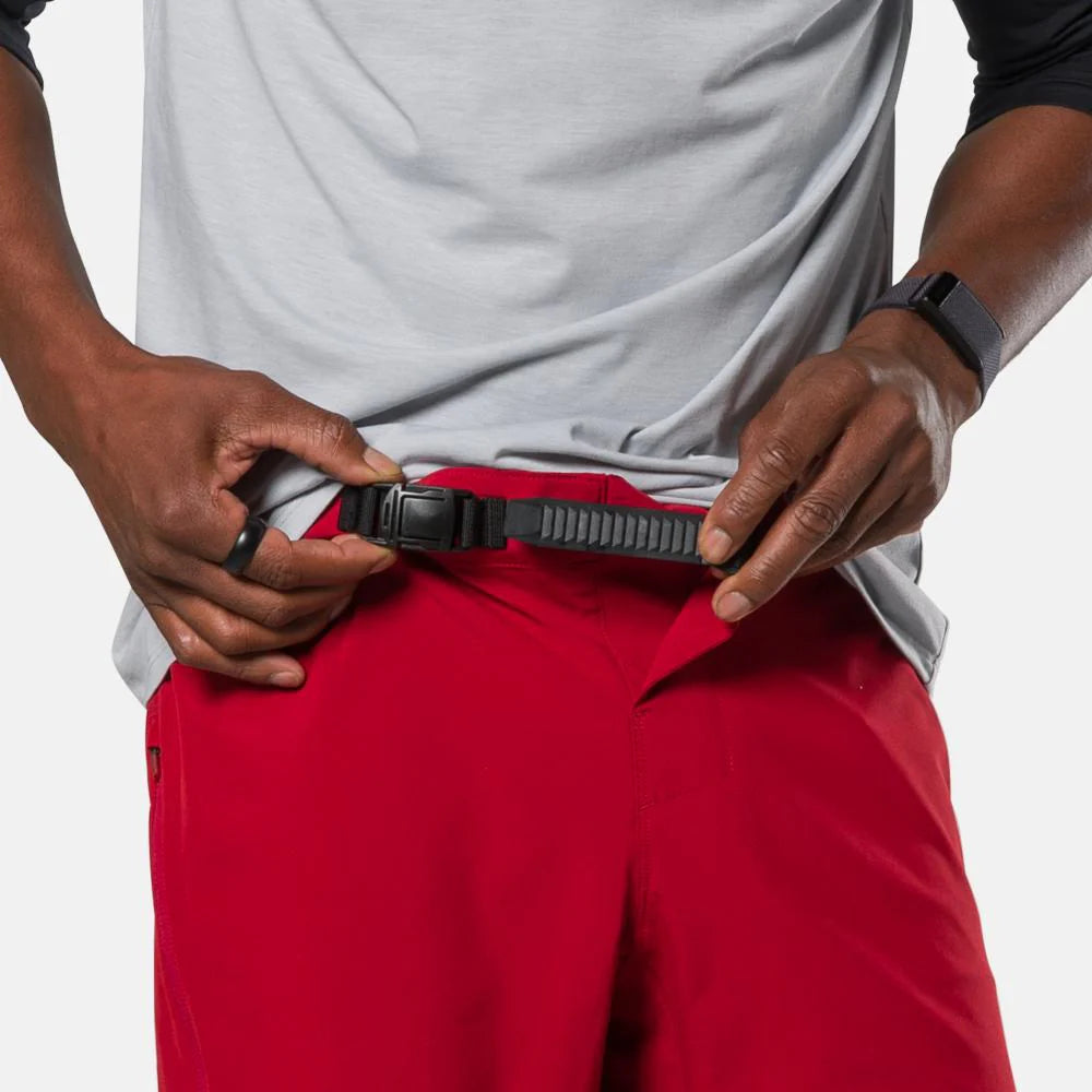 Person wearing red pants and a gray shirt, adjusting a black belt.