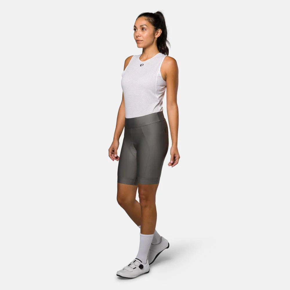 Woman wearing a white sleeveless top and gray bike shorts on a white background