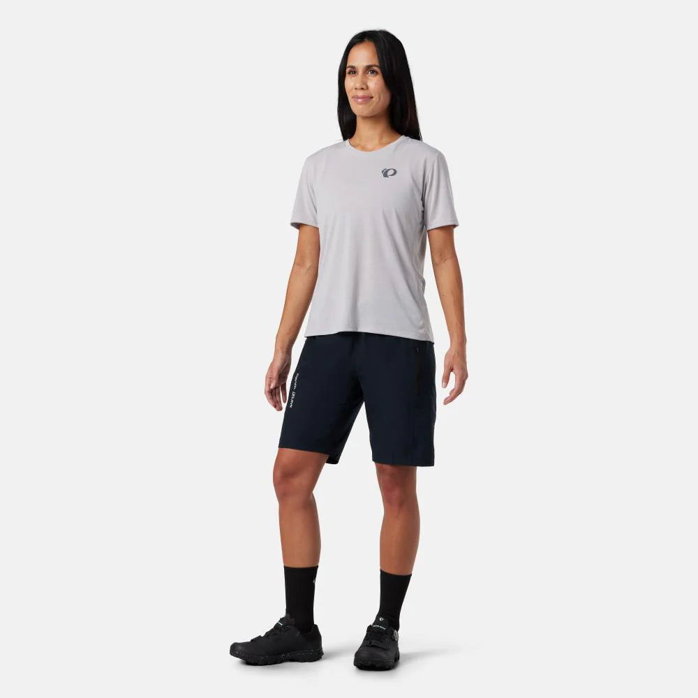 Woman wearing a light gray t-shirt and dark shorts on a white background