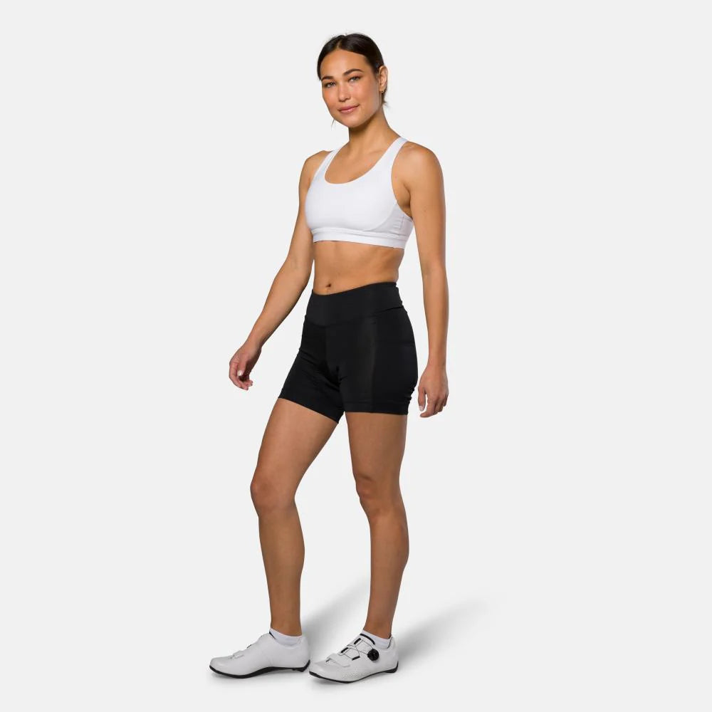 Woman wearing a white sports bra and black shorts on a white background