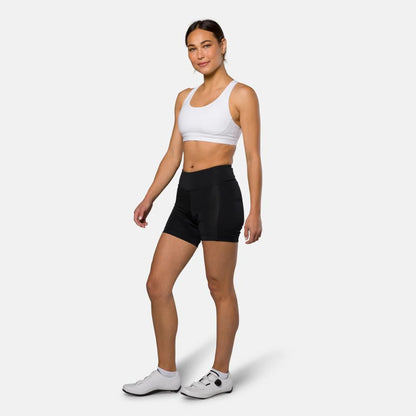 Woman wearing a white sports bra and black shorts on a white background