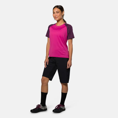Woman wearing a pink and purple athletic shirt with black shorts on a white background