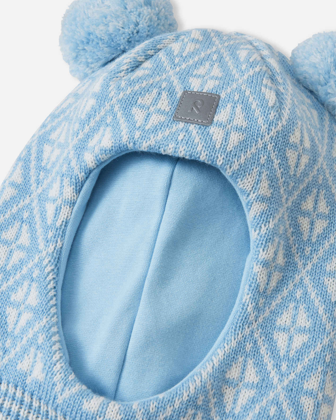 Blue knitted hat with pom-poms on a light gray background