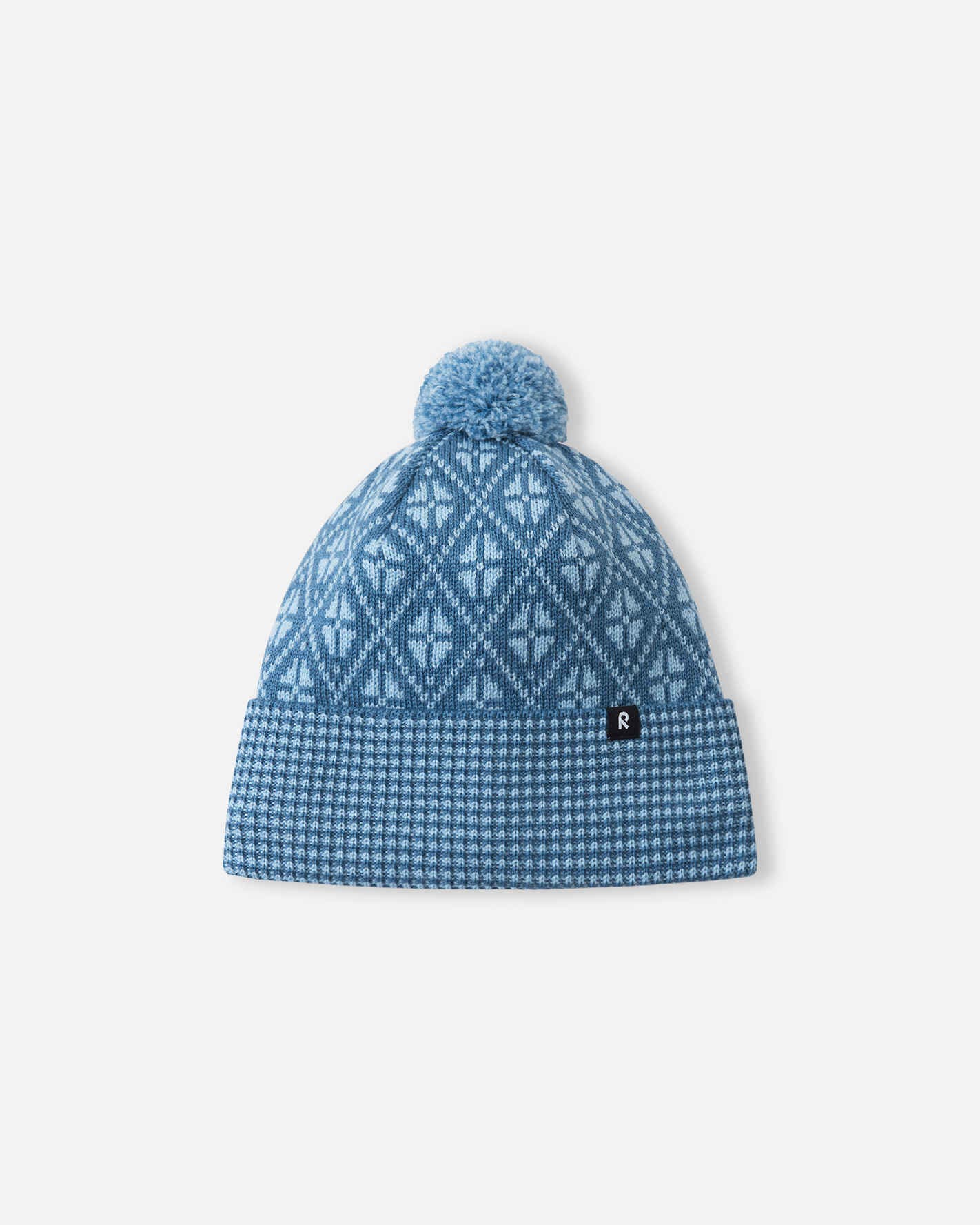 Blue patterned beanie with pom-pom on a light gray background
