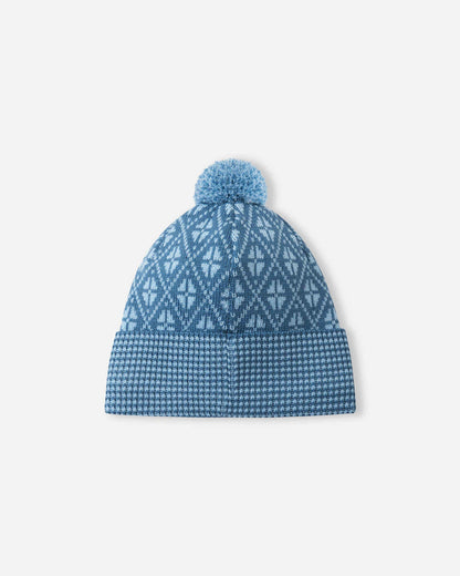 Blue knit beanie with a patterned top and pom-pom on a light gray background