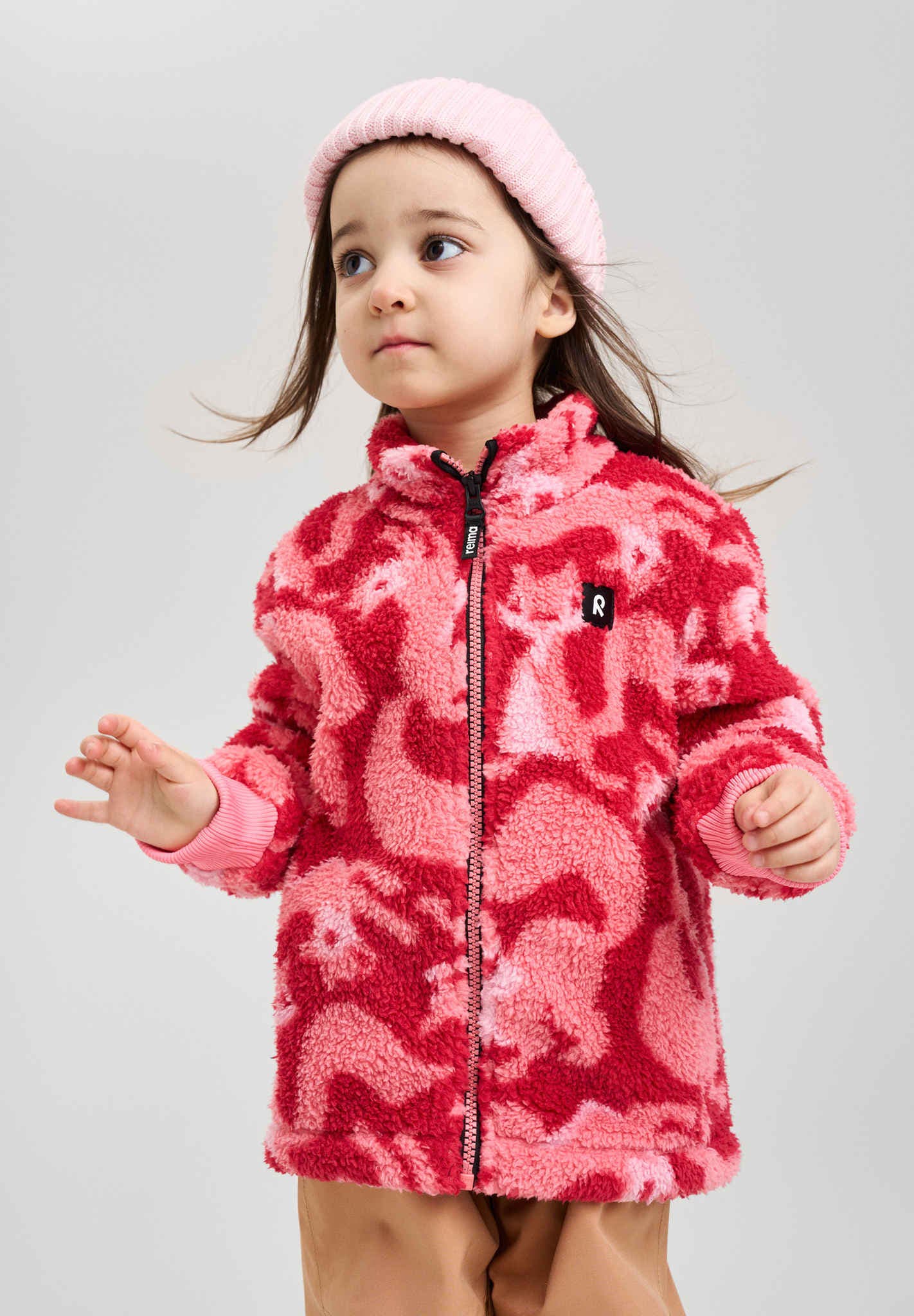 Child wearing a pink fleece jacket with animal pattern on a gray background
