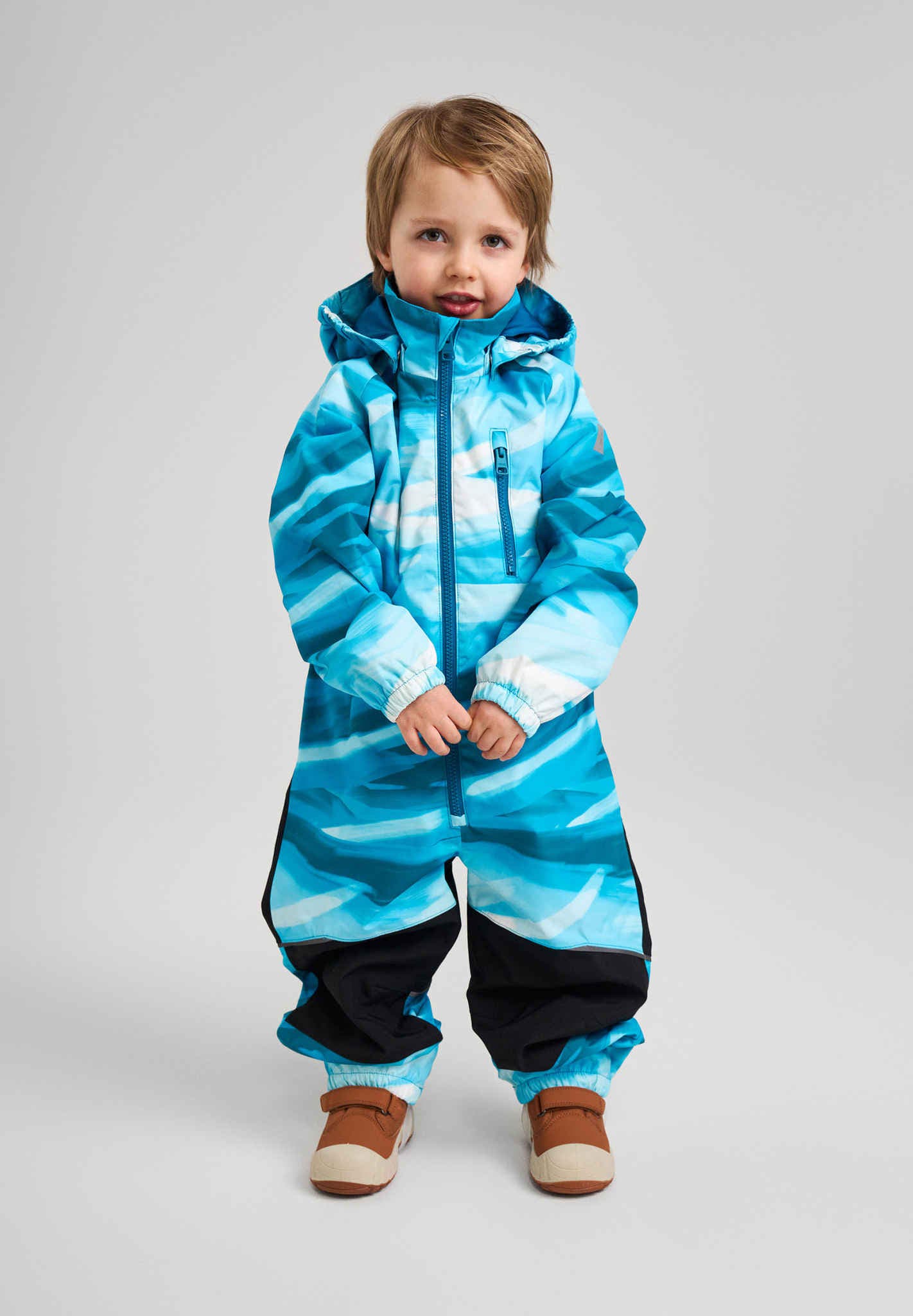 Child wearing a blue and black striped snowsuit on a gray background