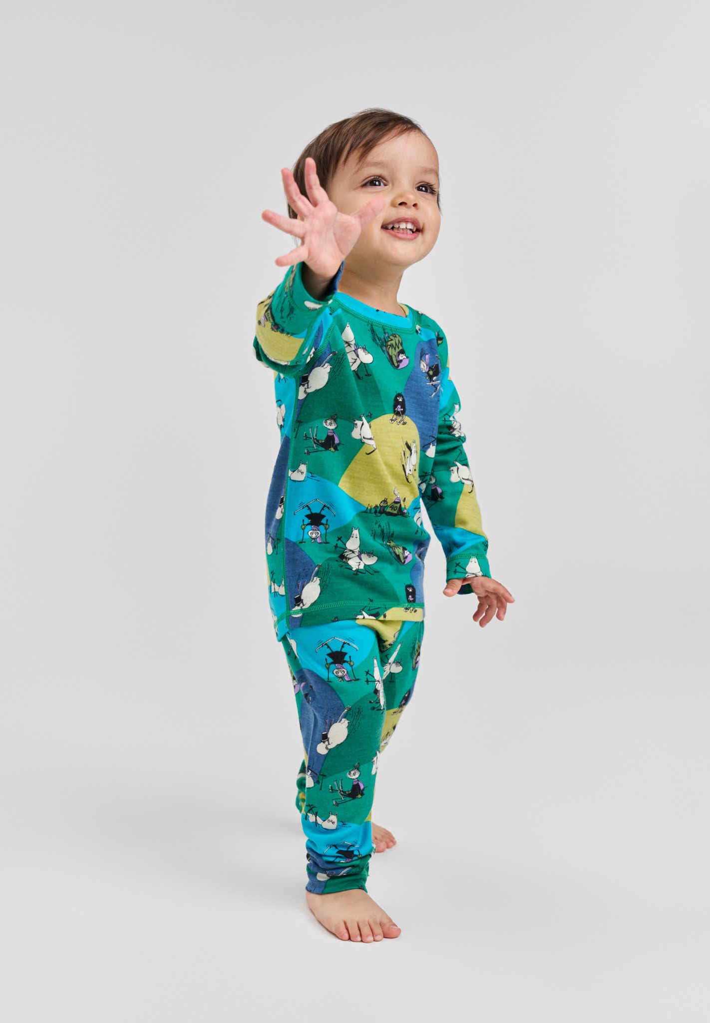 Child wearing a colorful onesie with animal patterns on a plain background