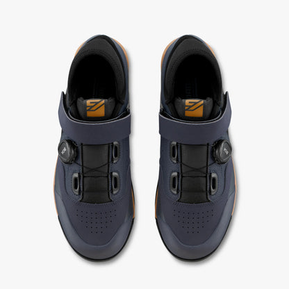 Pair of blue cycling shoes with black buckles on a white background