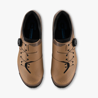 Pair of tan cycling shoes with black laces on a white background