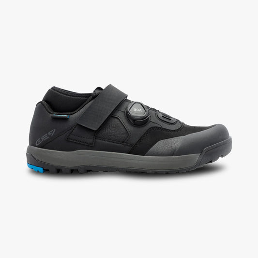 Black athletic shoe with a blue sole on a white background