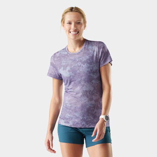 Woman wearing a purple patterned shirt and blue shorts on a white background