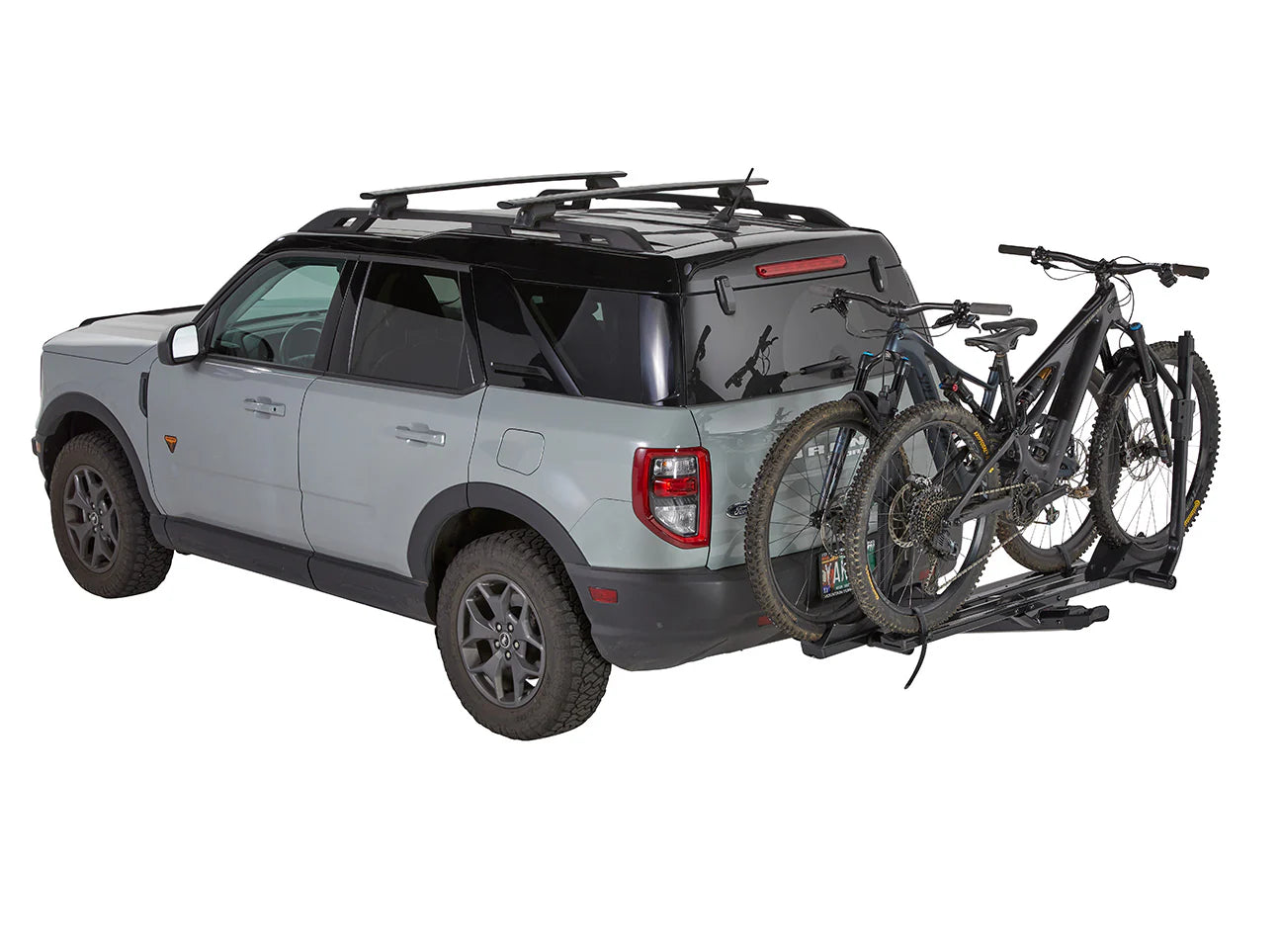 Gray SUV with a bike rack carrying two bicycles on a white background