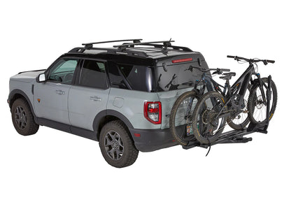 Gray SUV with a bike rack carrying two bicycles on a white background