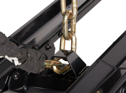 Person wearing gloves using a chain to operate a black mechanical device on a white background
